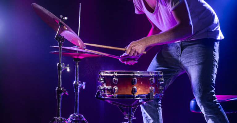 A drummer plays drums on a blue background. Beautiful special effects of light and smoke. The process of playing a musical instrument